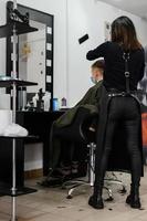 Teenager bekommt während einer Pandemie im Friseursalon einen Haarschnitt, Haarschnitt und trocknet Haare nach einem Haarschnitt. foto