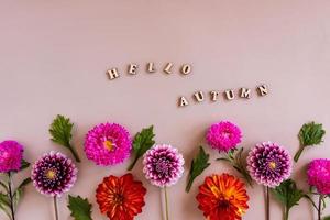 Draufsicht auf die florale Grenze des Herbstes bunte Blumen und Text aus Holzbuchstaben - hallo Herbst. Pastellhintergrund. foto
