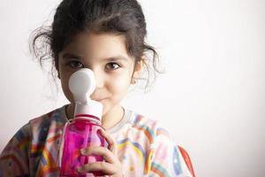 kleines Mädchen trinkt Wasser aus einer rosa Plastikflasche foto