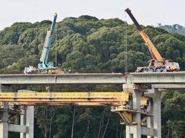 Mobilkräne, die an Betonbrückenträgern arbeiten foto