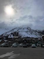 parken und steinhäuser, gebäude, geschäfte, auftanken in einem wunderschönen bergwinterresort mit hohen berggipfeln und schneebedeckten felsen vor blauem himmel. Georgien, Tiflis, 17. April 2019 foto