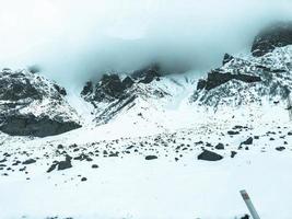 schöne bergkalte winterlandschaften mit hohen berggipfeln nebel und schneebedeckten felsen zum snowboarden und skifahren vor blauem himmel foto