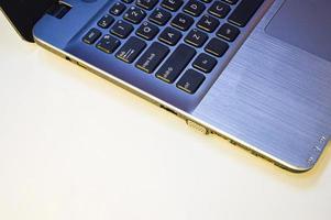 Seitenansicht linke Seite des Laptops auf weißem Hintergrund und mit gelb-orangem Licht foto