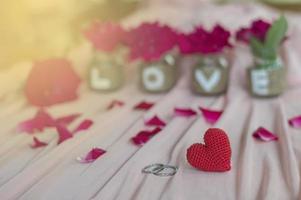 rotes herz, ringe, rose und tafel auf rosa stoff für valentinstag oder hochzeitshintergrund foto