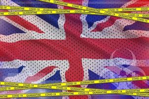 großbritannien-flagge und covid-19-quarantäne-gelbband. Coronavirus- oder 2019-ncov-Viruskonzept foto