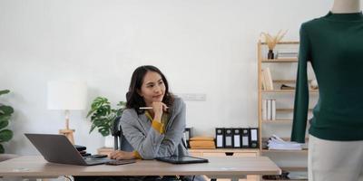 lächelnder Designer, glückliche Stylistin, asiatische junge Frau, Mädchen mit Laptop-Computer, Online-Bestellung im Home Office, Verkauf von modischer Kleidung, Inhaber von Startups, E-Commerce-Unternehmer, kleines KMU-Unternehmen. foto