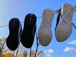 Zwei Paar Turnschuhe trocknen auf einer Wäscheleine vor blauem Himmel. foto