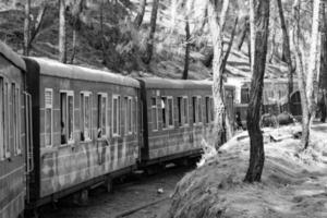 spielzeugeisenbahn, die sich am berghang bewegt, schöne aussicht, eine seite des berges, eine seite des tals, die auf der eisenbahn zum hügel fährt, inmitten grüner naturwälder. spielzeugeisenbahn von kalka nach shimla in indien-schwarz und weiß foto