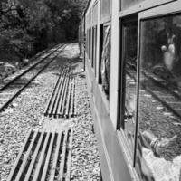 spielzeugeisenbahn, die sich am berghang bewegt, schöne aussicht, eine seite des berges, eine seite des tals, die auf der eisenbahn zum hügel fährt, inmitten grüner naturwälder. spielzeugeisenbahn von kalka nach shimla in indien-schwarz und weiß foto