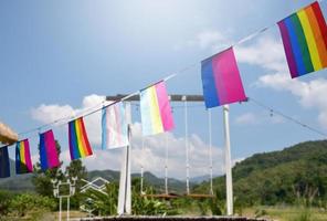 regenbogenfahnen und lgbtq-plus-flaggen wurden an einem sonnigen tag an draht gegen den blauen himmel gehängt, weicher und selektiver fokus, konzept für lgbtq-plus-gender-feiern im stolzmonat auf der ganzen welt. foto