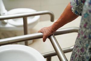 asiatische ältere alte patientin benutzt toilettenstützschiene im badezimmer, handlauf-sicherheitshaltegriff, sicherheit im pflegekrankenhaus. foto