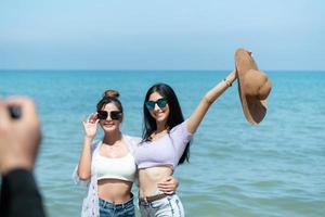 lgbt-paare, die durch asien reisen, schwimmen glücklich am sandstrand mit dem wunderschönen blauen meer foto