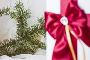ein weihnachtsgeschenk verziert mit einer schönen schleife auf hellem hintergrund mit einem tannenzweig. Geschenke, Freude, Überraschung. selektiver Fokus. das konzept von weihnachten und neujahr foto