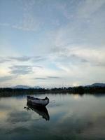 Traditionelles Holzboot, das auf dem Wasser des Sees Limboto, Gorontalo, Indonesien schwimmt. kleines hölzernes Ruderboot auf einem ruhigen See foto