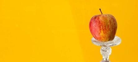 roter Apfel in einer Glasvitrine mit gelbem Hintergrund foto