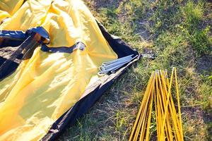 Befestigungsbögen aus Aluminium, Heringe für die Installation des gelben Touristenzeltes und wasserdichtes Tuch auf dem Boden. leichte Ausrüstung für den Tourismus. Outdoor-Aktivitäten, Montageanleitungen, heimischer Ökotourismus. foto