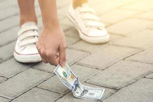 glückliche frau pflückt einen hundert-dollar-schein vom boden. foto