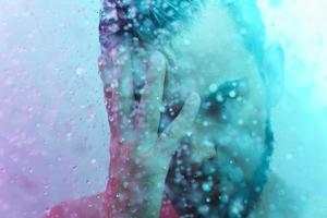 Porträt eines jungen gutaussehenden Mannes unter Wasserfluss foto