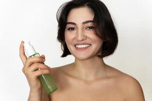 schöne brünette frau mit glatter haut mit einer flasche reinigungsgel foto