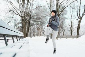 Frau, die sich vor ihrem Jogging-Training im Winter und an verschneiten Tagen aufwärmt foto
