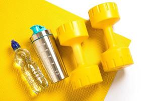 gelbe Hanteln, Fitnessmatte, Wasserflasche und Proteinshaker foto