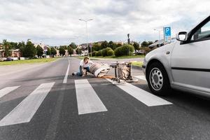 Schockierte Mutter auf dem Zebrastreifen nach einem Autounfall, als das Fahrzeug ihren Kinderwagen trifft foto