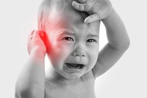 Weinendes Baby, das unter Ohrenschmerzen leidet foto
