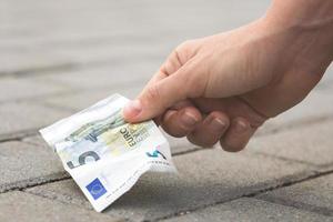 Frau pflückt fünf Euro-Banknoten vom Boden foto