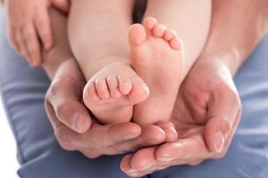 Die Hände des Vaters halten die Füße seines Babys foto