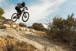 professioneller radfahrer, der während der bergabfahrt auf seinem fahrrad springt foto