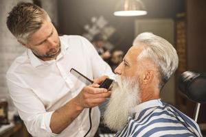 Schöner älterer Mann, der seinen Bart stylt und trimmt foto
