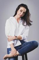 schöne Frau mittleren Alters mit weißem Hemd und Jeans im Fotostudio foto