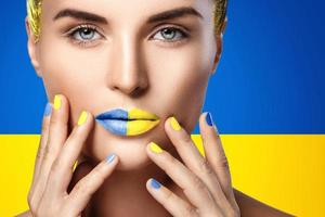 Selbstbewusste Frau mit gelb-blauem Lippenstift und ukrainischer Flagge im Hintergrund foto