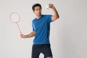 ein Badmintonspieler in Sportbekleidung steht mit Schläger und Federball. foto