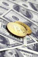 Goldene Bitcoins liegen auf vielen Dollarscheinen. das konzept, den preis von bitcoin gegenüber dem us-dollar zu erhöhen foto