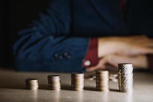 geschäftsbuchhaltung mit geldsparen mit der hand, die münzen in das krugglaskonzept einlegt finanziell foto