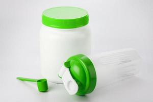 grüner proteinshaker, schaufel und glas auf weiß foto