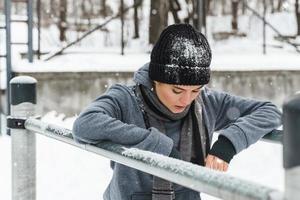 sportliche Frau während ihres Wintertrainings im Freien auf Barren foto