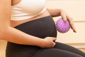 schwangere frau, die ihren bauch mit stacheligem gummiball massiert foto