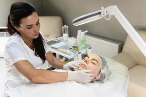 Professioneller Permanent-Make-up-Künstler, der Anästhesiecreme aufträgt foto