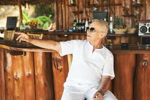 glücklicher älterer mann, der in der strandbar sitzt foto