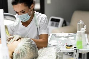 Permanent Make-up-Künstlerin und ihre Kundin während des Lippenröten-Verfahrens foto