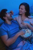 junges und glückliches paar, das popcorn isst und filme anschaut foto