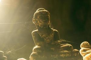 Nahaufnahme von steinernen Buddha-Statuen, die in einem Spinnennetz in einer Höhle bedeckt sind. foto