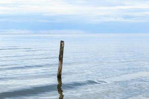 Meereslandschaft mit gebrochenem Pierpfosten, der aus dem Wasser ragt. foto
