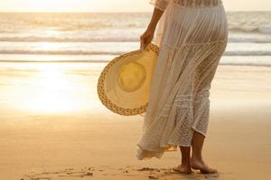 Frau, die ein schönes weißes Kleid am Strand trägt foto