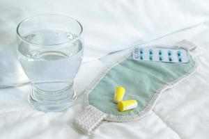 blisterpackung mit schlaftabletten, augenbinde und glas wasser foto