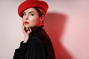 Porträt der jungen schönen Frau mit roter Baskenmütze foto