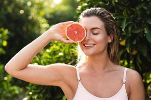 schöne Frau mit glatter Haut mit einer Grapefruit in ihren Händen foto