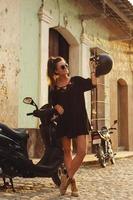 Frau, die Roller durch die alten Straßen der Stadt fährt foto